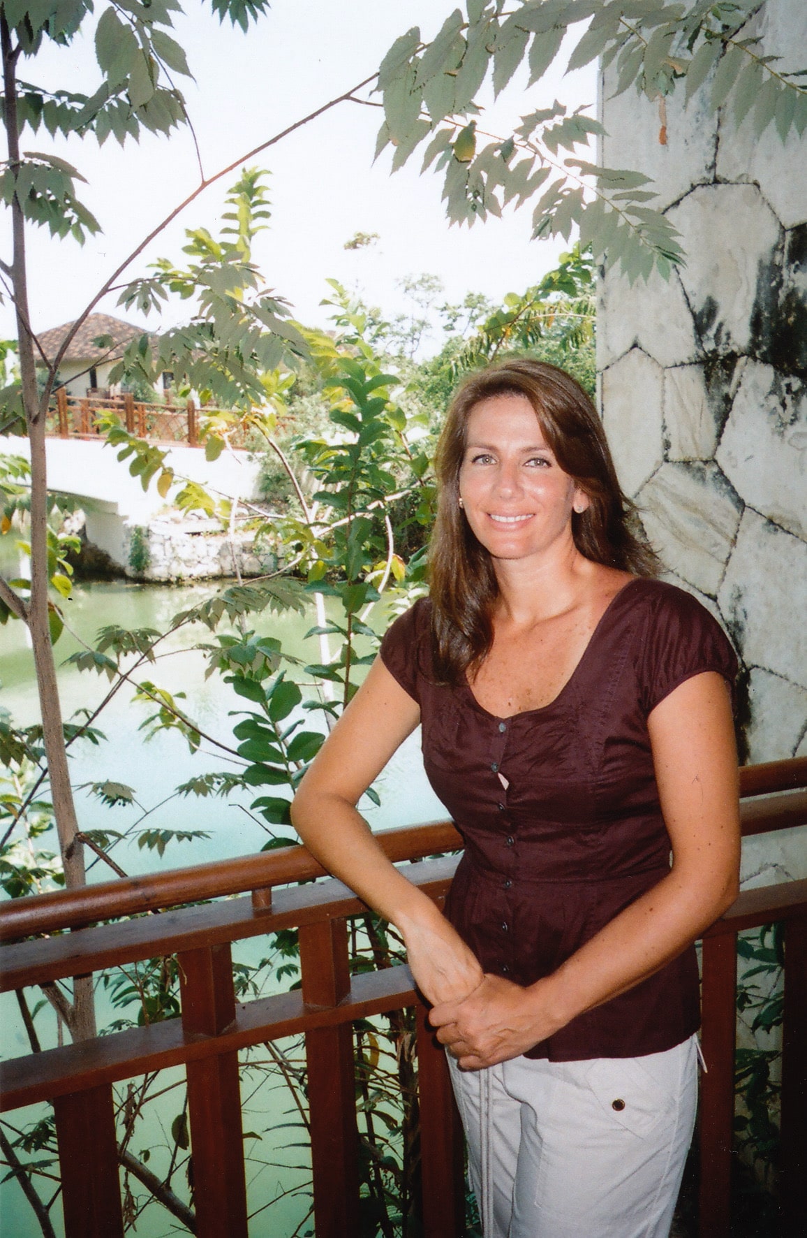 Guadalupe Vargas Stepanenko standing beside a wooden railing, surrounded by greenery.